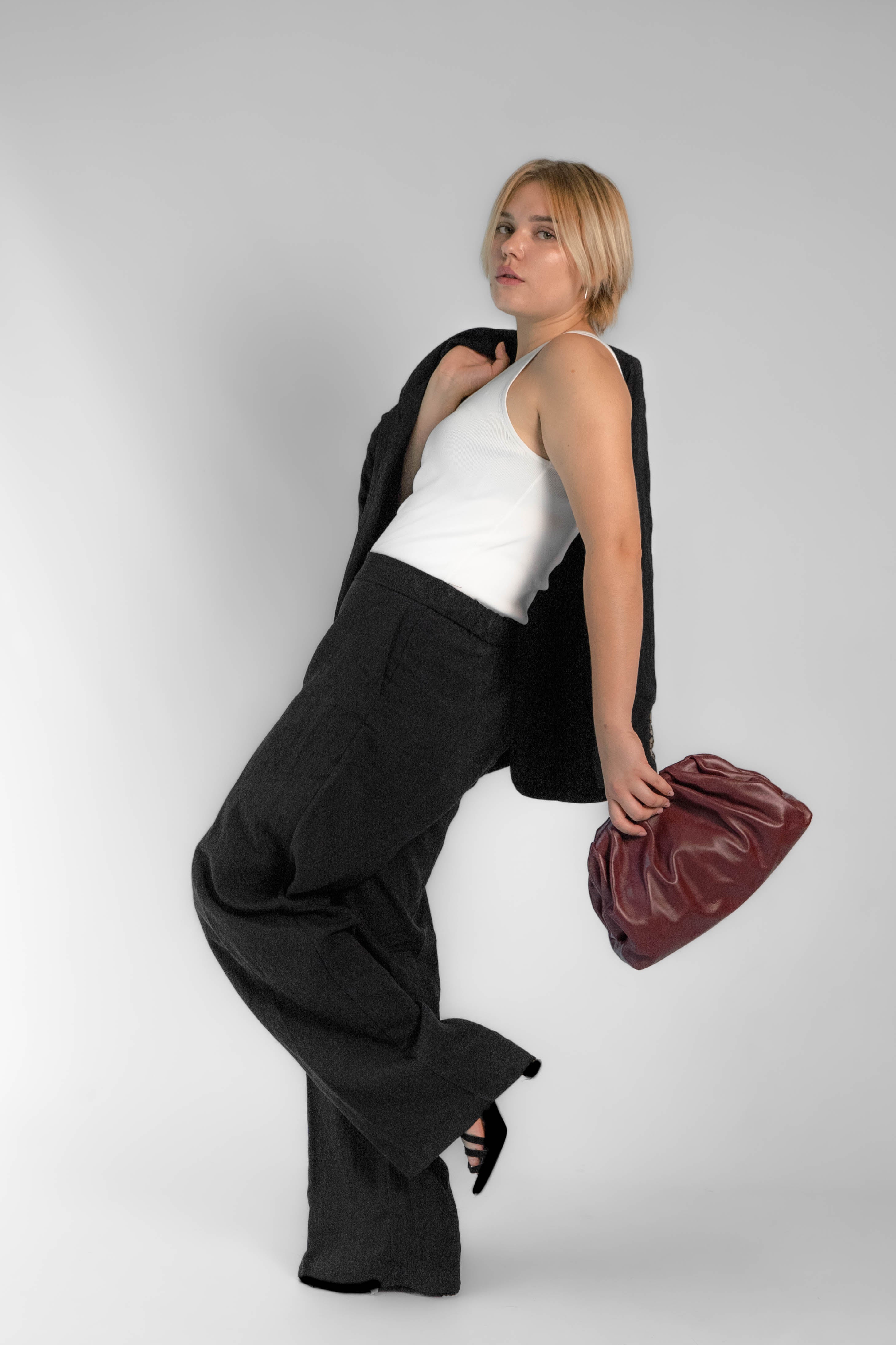 Bolso Clutch Bag Scarlet burdeos de diseño moderno sobre fondo neutro.